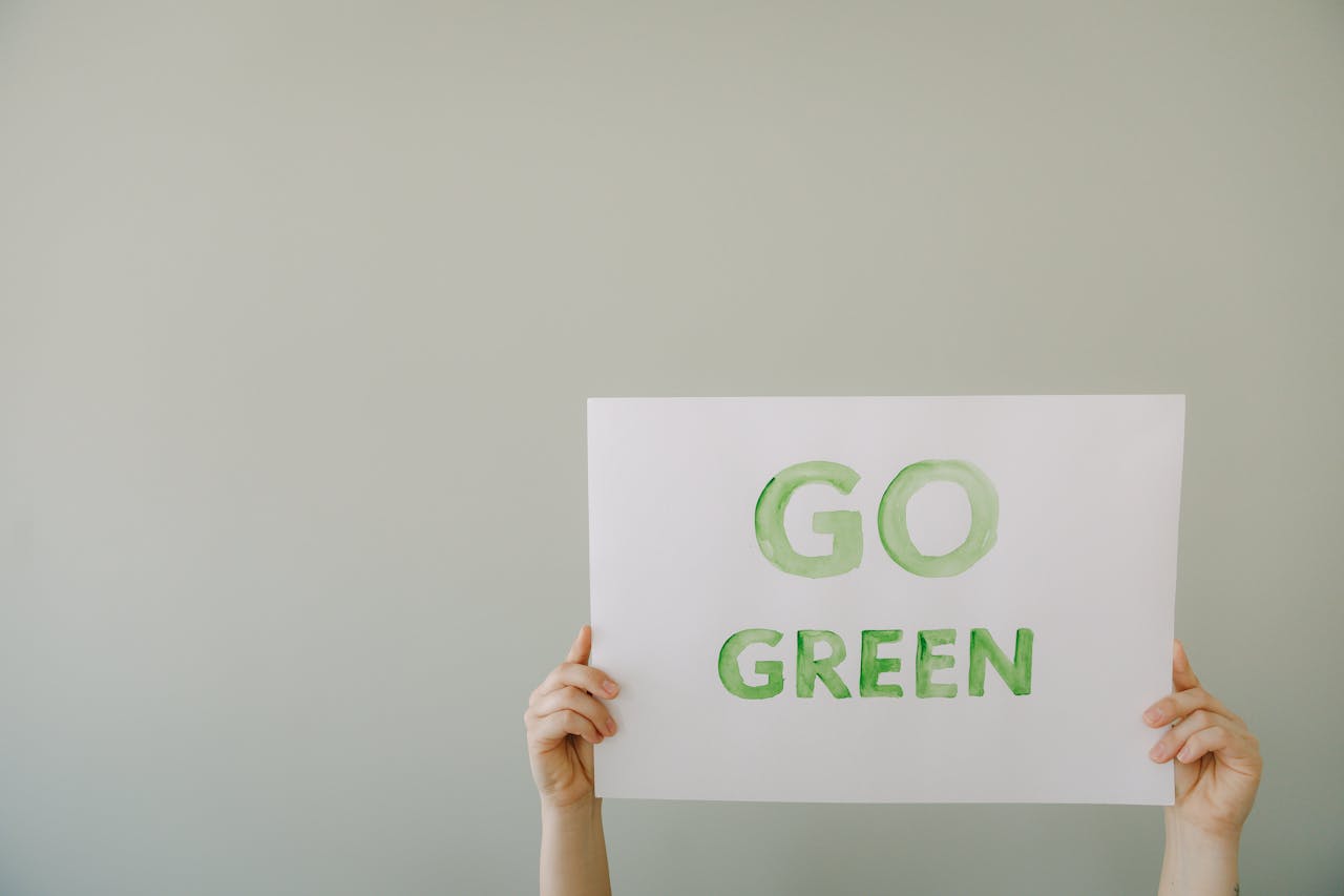 Image of hands holding a 'Go Green' sign to promote environmental awareness and sustainability.
